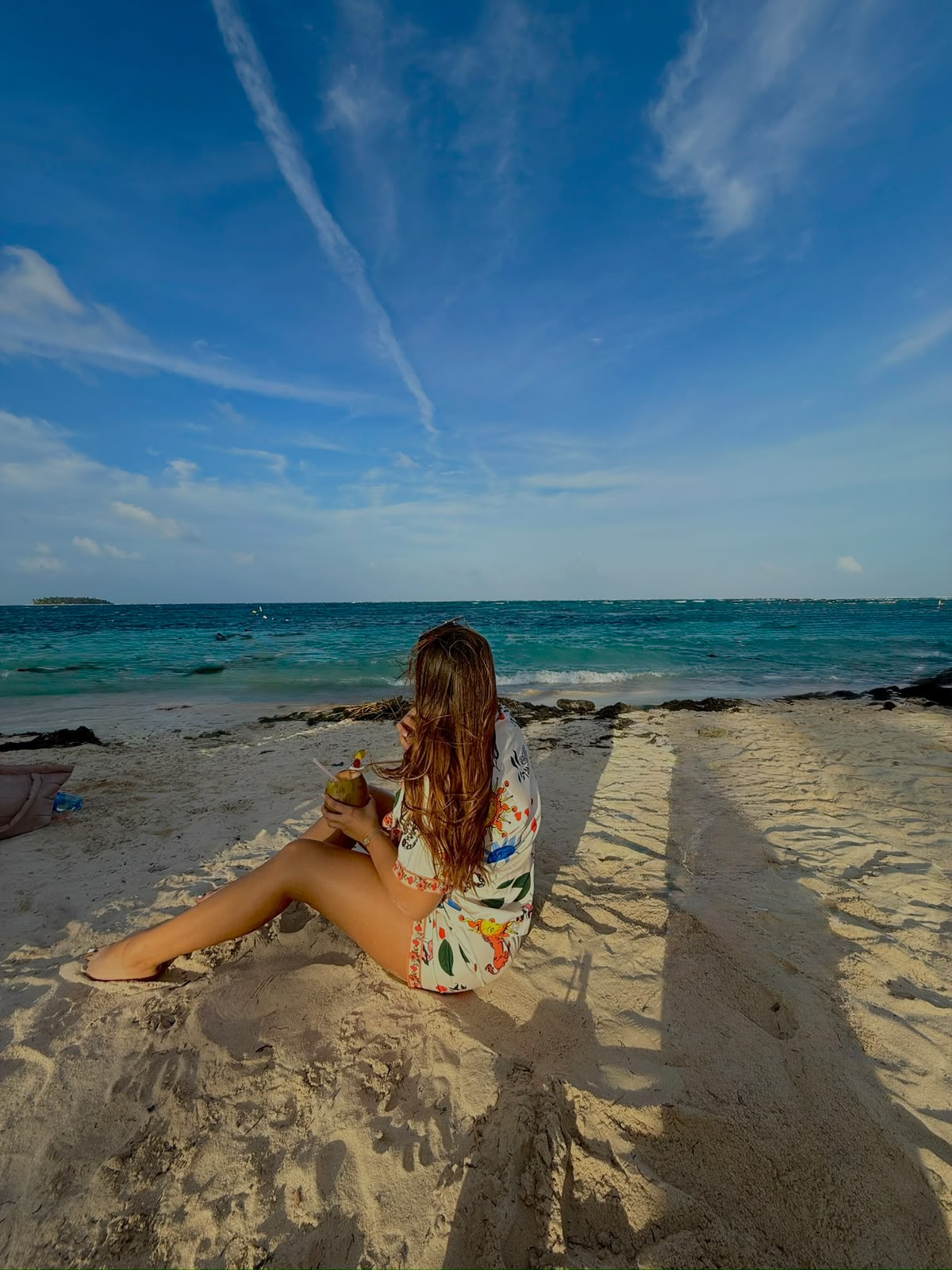 Mujer relajada frente al mar tomando un coco
